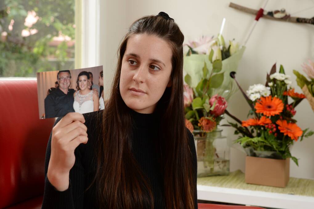 SHATTERED: Meg Aston holds a photo of her and her dad Jack in happier times, with flowers of support in the background. Picture: Kate Healy 
