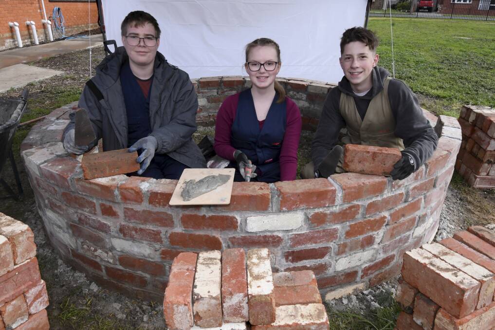 TEAMWORK: Berry Street School students Alex, Gemma and Kayde are working together to create a rustic vegetable patch using recycled bricks. Pictures: Lachlan Bence 