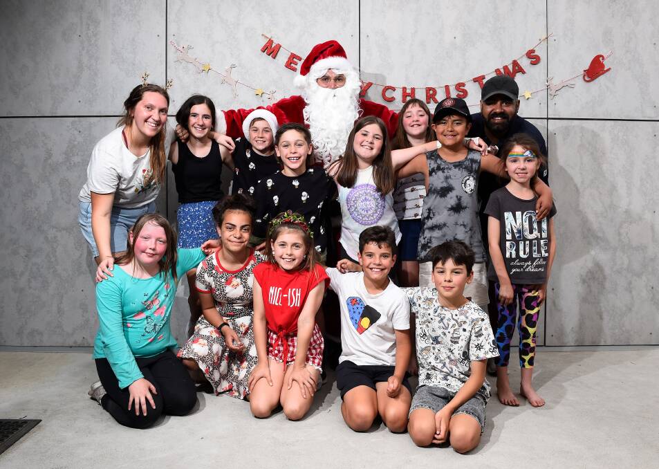 JOY: BADAC Koori youth engagement officer Nikki Bell and youth services team leader Aaron Clarke with Santa and a group of children at the BADAC Christmas tree event. Picture: Adam Trafford 