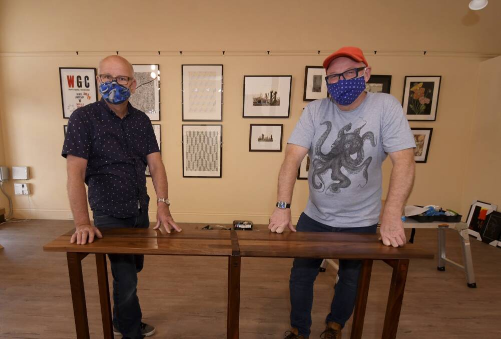 EXHIBIT: Helmut Stenzel and Cliff Adeney set up the Soldiers Hill Artist Collective exhibition at Art Space. Picture: Lachlan Bence 