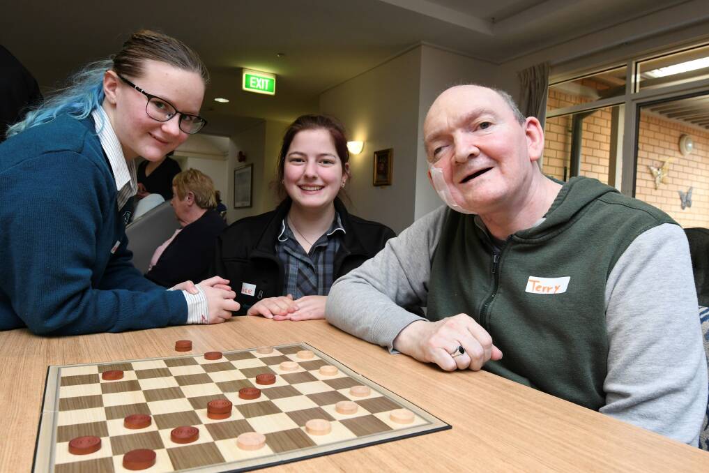 BRIDGING A GAP: Woodmans Hill Secondary College students Kaylah Tucker, Year 11 and Alice Ashley, Year 12, play checkers with Geoffrey Cutter Centre resident Terry McGarry. Picture: Lachlan Bence 