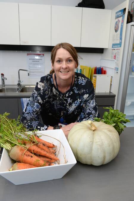 FRESH FOOD: Ballarat Community Health health promotion officer Melissa Farrington picks vegetables fresh from the centre's garden. Volunteers cook for food relief programs at the centre each week. Picture: Kate Healy