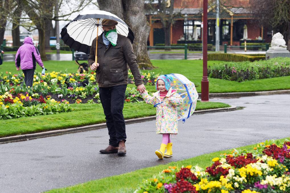WET WEATHER: Matt Briody and Eden Briody, 3, brave the rain at the Ballarat Botanical Gardens on Saturday.