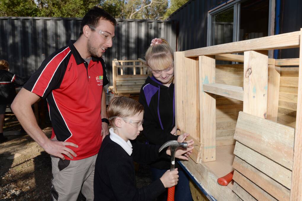 TOGETHER: Mount Clear College Hands on Learning program coordinator Brett Domaschenz works with students Jahi, Year 7, and Kyla, Year 8 to nail a piece of wood to the dog kennel. Picture: Kate Healy 