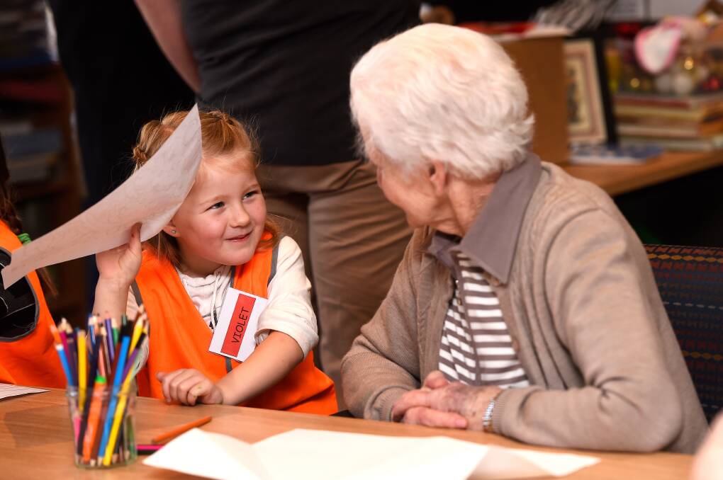 BONDING: Resident Val talks with kindergarten child Violet while she completes a drawing. 