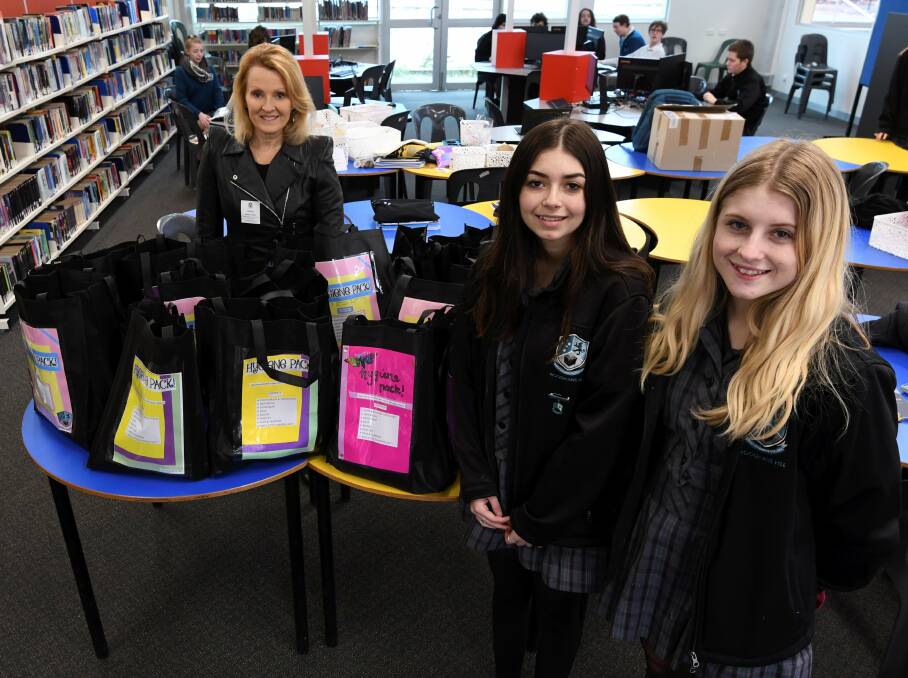 DONATE: Woodman's Hill Year 12 students Jasmine White and Rhiannon Shaw donate hygiene packs to Alison from WRISC Family Violence Support. Picture: Lachlan Bence 