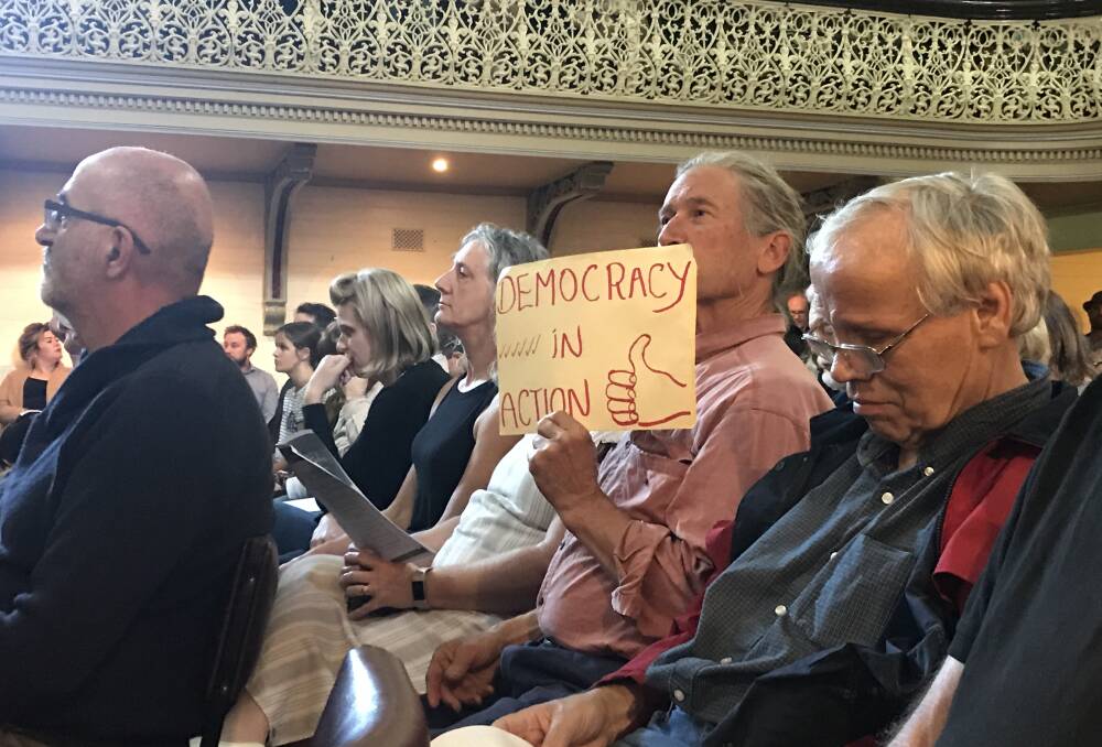 One of the many signs held aloft during the meeting. Photo: Rochelle Kirkham.