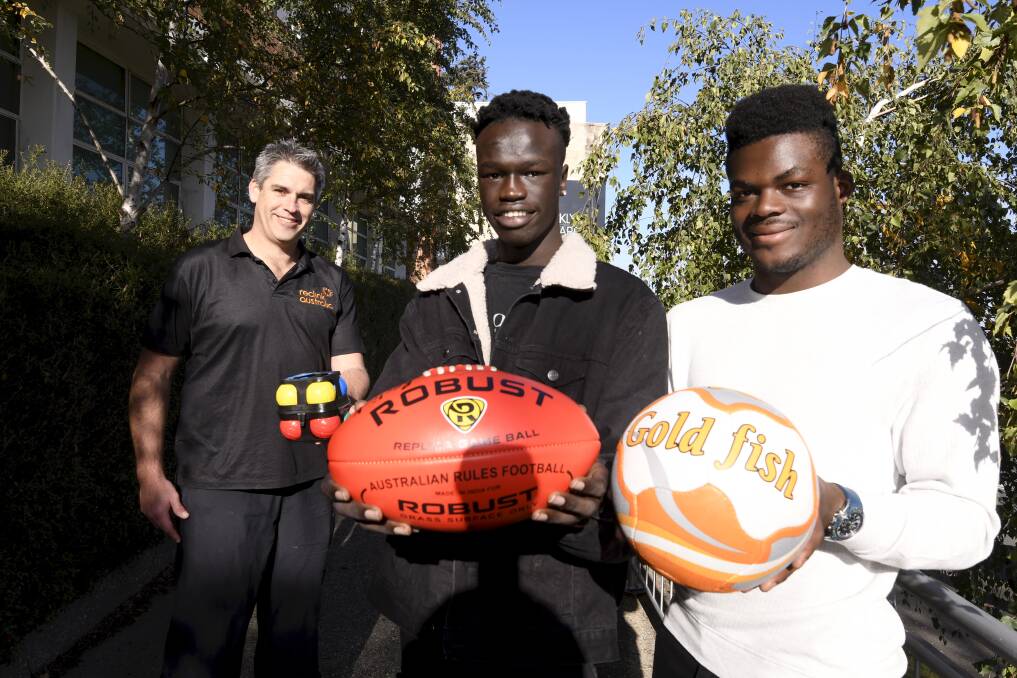 STAY ACTIVE: RecLink's Andrew Dunn with Centre For Multicultural Youth's Magbul Choul and Lunorphare Folly who received a donation of new sporting equipment. Picture: Lachlan Bence 