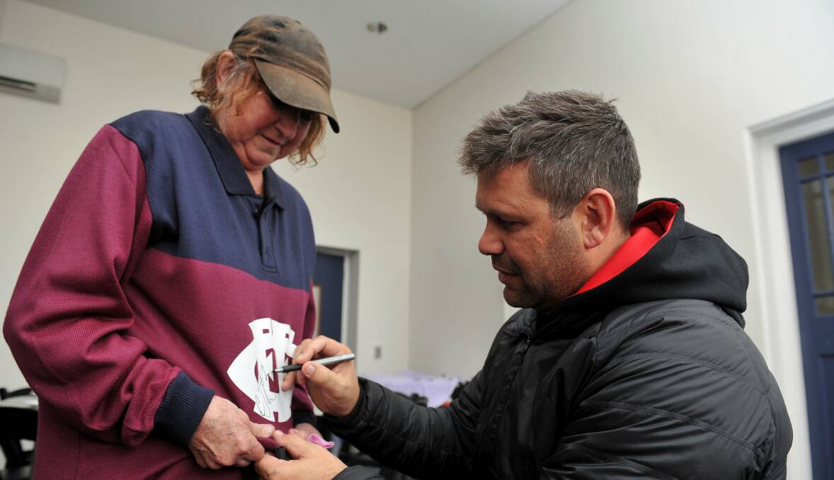 SURREAL: Flying Boomerangs development coach Chris Johnson signing Beverley Jewell's vintage Fitzroy Lions jumper. Photo: Lachlan Bence.