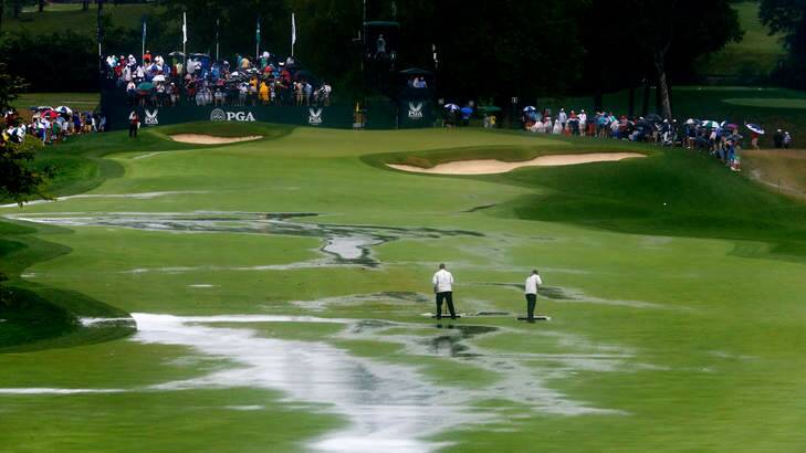 Spectator sport:  Members of the grounds crew squeegee the first fairway earlier today. Photo: Getty Images