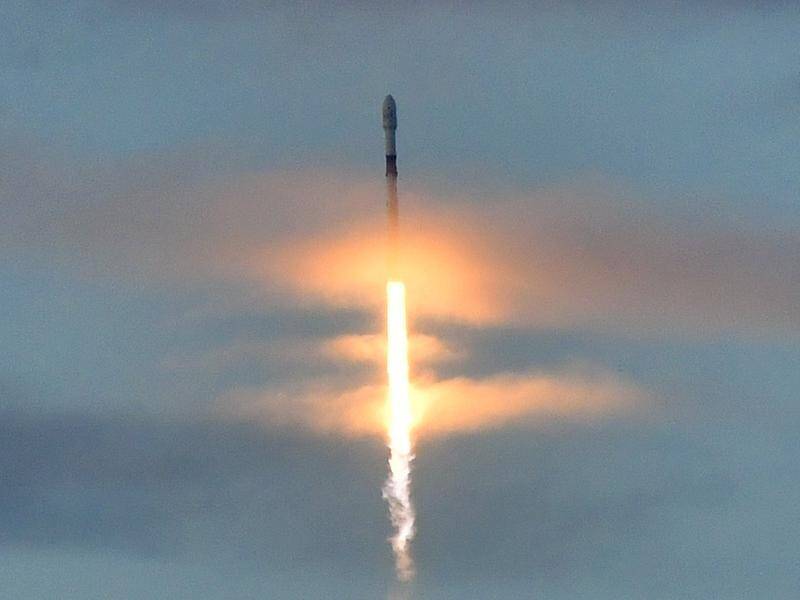 The SpaceX Falcon 9 rocket carrying 10 Iridium Communications satellites blasts off through clouds.