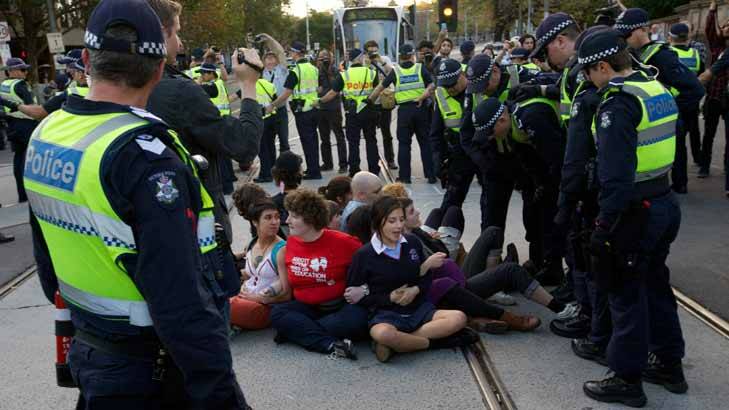 Teenage students sat on tram tracks on Spring Street during the heated protest. Photo: Jason South