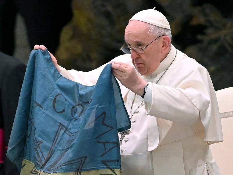 Pope Francis shows a flag of Ukraine sent to him from the town of Bucha.