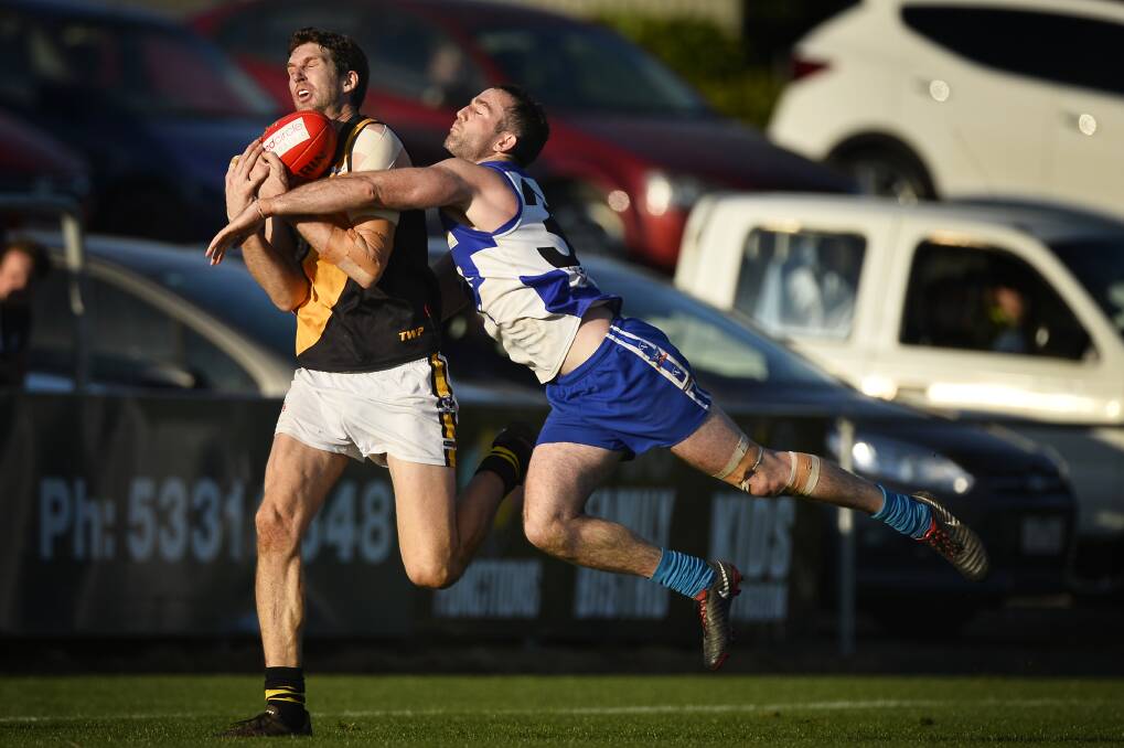 Michael Searl of the Tigers marks the ball ahead of James Petrie of the Roos. Picture: Dylan Burns