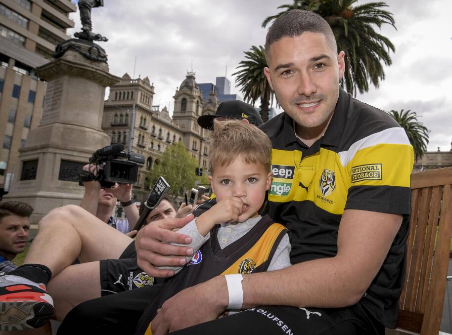 EXCITED: Shaun Grigg in the motorcade with his three-year-old son Sonny taking in all the colour and atmosphere of the grand final parade. Picture: Eddie Jim (The Age) 