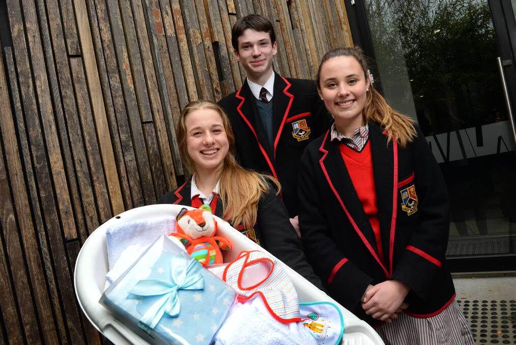 Special gift: Ballarat Clarendon College year 11 students Milly Kimpton, Patrick Mayman and Kate Walker with one of the baby bundles that will be presented to new mothers in Papua New Guinea’s Milne Bay Province. PICTURE: ADAM TRAFFORD