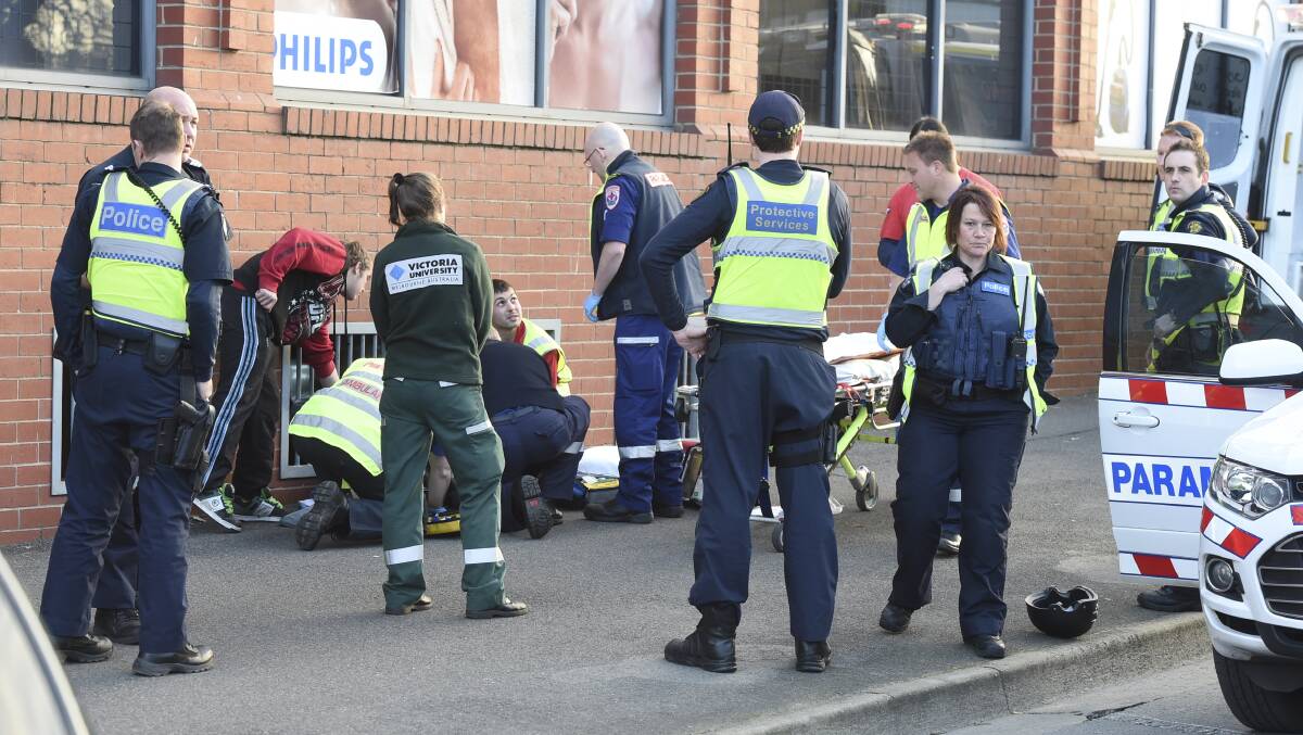 Paramedics attend to a 19-year-old man hit by a car while running from PSOs at Ballarat station. PICTURE: Lachlan Bence 