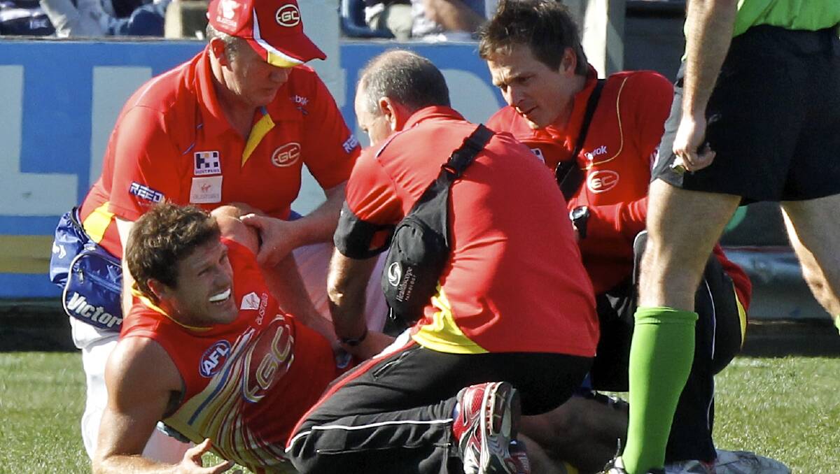 Campbell Brown seen to by medical staff while playing for the Gold Coast.