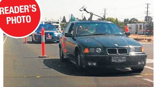 A reader captured this shot of the man waving a vaccum part out the sunroof of his BMW during the police chase.