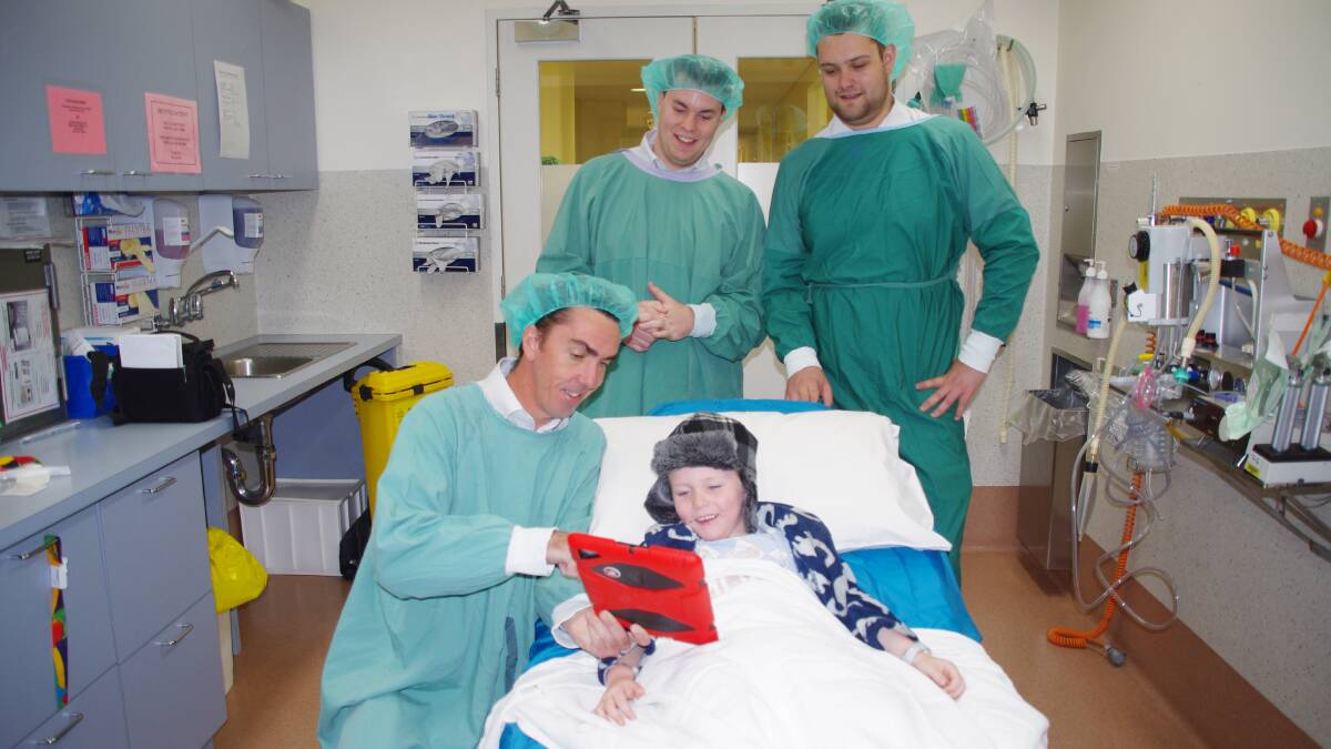 Ballarat Base Hospital patient Riley, 5, checks out the iPad with Telstra Business Centre Plus IT’s Michael Cushing (kneeling), Heath Trengove and Jordon Mudge.