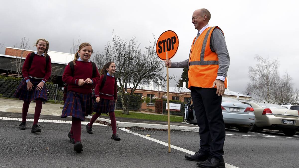 After a minor bingle out the front of St Francis Xavier school on Monday, the principal has been manning the crossing to ensure safety. Principal Paul Bissinella helps pupils Milly Sharp, Maddie Bolt and Kate McClure cross the road. FILE IMAGE