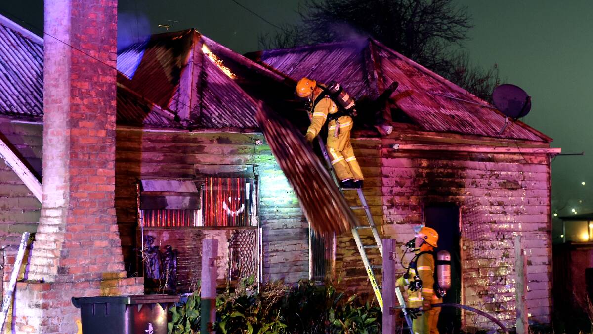 A firefighter hoses flames in the Ballarat East miners cottage. PICTURE: JEREMY BANNISTER
