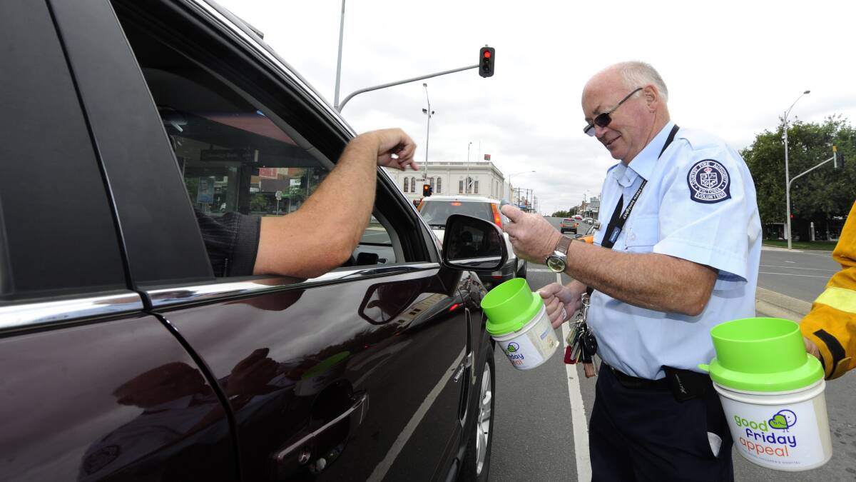 FILE PIC: CFA Firefighter Russell Smith collects donations with a Good Friday Appeal tin last year. Donation collectors have warned residents that legitimate charities would be identifiable through uniforms, ID tags and CFA gear.