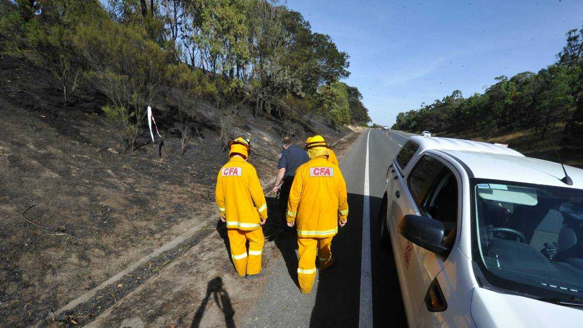 CFA members inspect fire damage at the Western Freeway on Saturday. PICTURE: LACHLAN BENCE