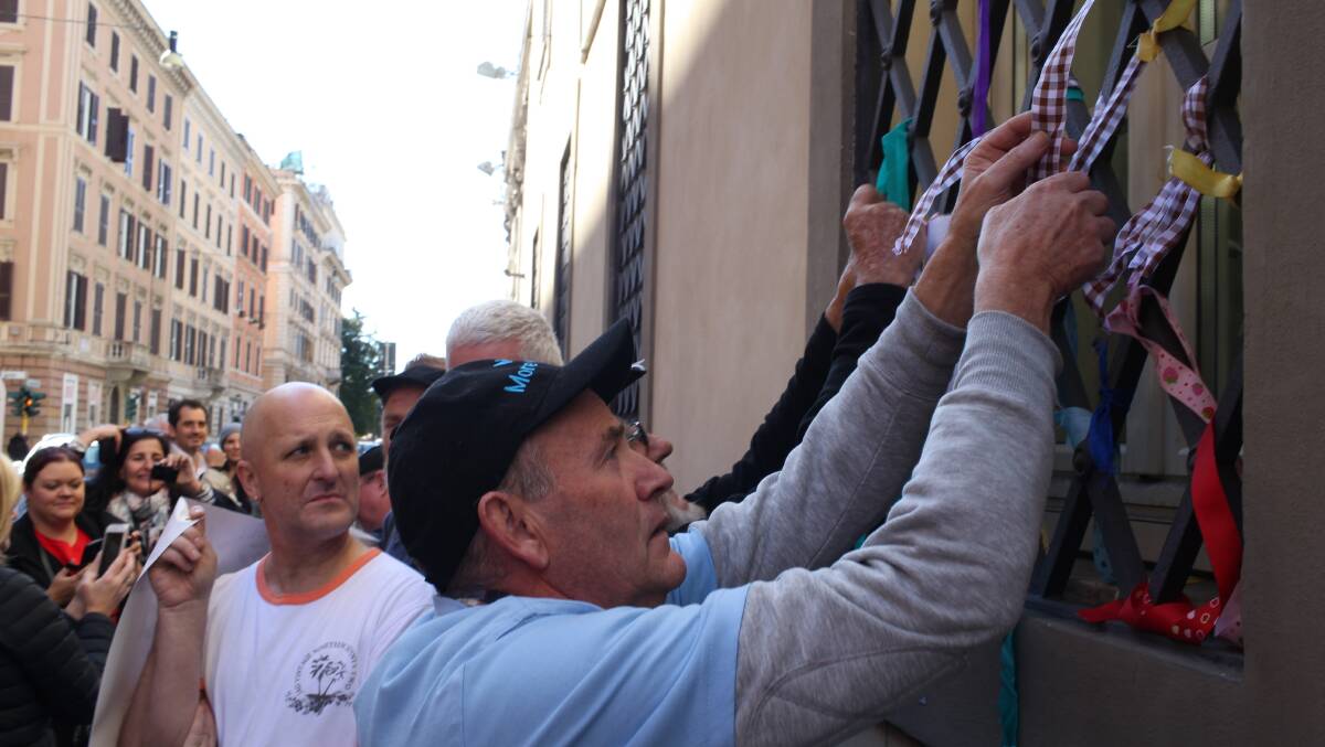 LOUDER: Gary Sculley ties a ribbon on Domus Australis, the pilgrims house in Rome. Andrew Collins looks on.  