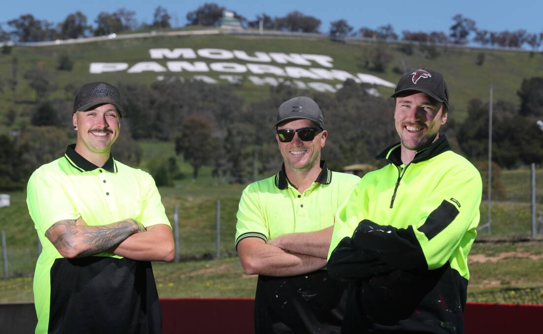 FRESH COAT OF PAINT: Coulton Rielly, Matt Shawcross and Liam Beattie have been painting the Mount Panorama sign so it looks its best for the Bathurst 1000. Photo: PHIL BLATCH