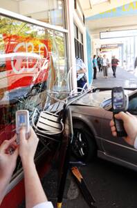 CRASH: People use their mobile phones to take a picture of the car that slammed into the  Sturt St cafe, Coffee by Design, in Ballarat yesterday afternoon.