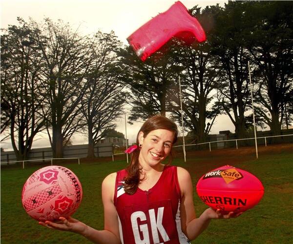COLOURFUL APPROACH: Danielle Masters models the pink football and netball that will be used in today's senior games, while a pink gumboot flies overhead. Her grandmother, Ann Hinton, has completed treatment for cancer.