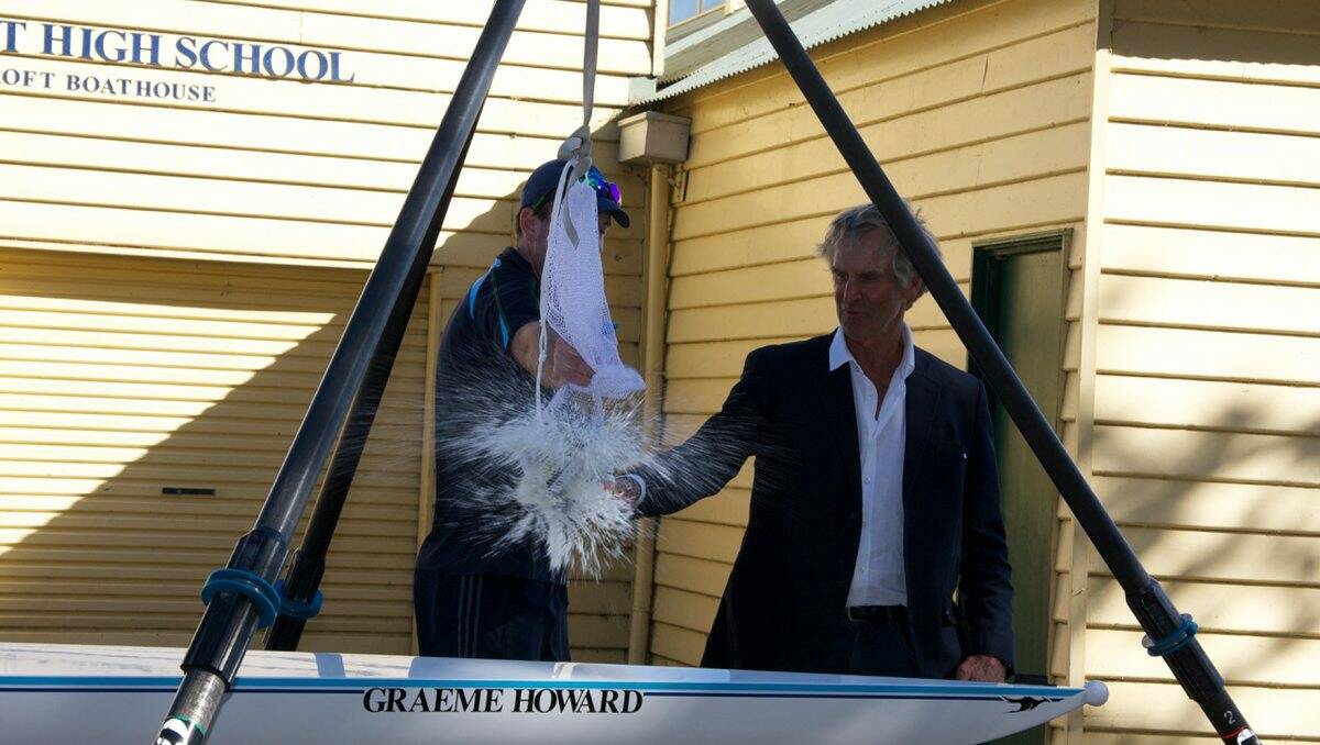 Dubbed: Ballarat High School rowing co-ordinator Rob Simmonds holds a champagne bottle as Graeme Howard smashes it to christen the new boat.