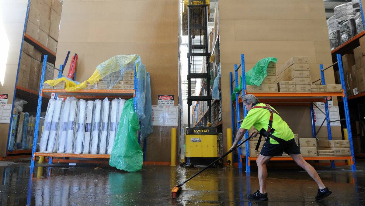 Ray Rajui works to mop up water after a fire scare at Super A-Mart Wendouree. PICTURE: JUSTIN WHITELOCK