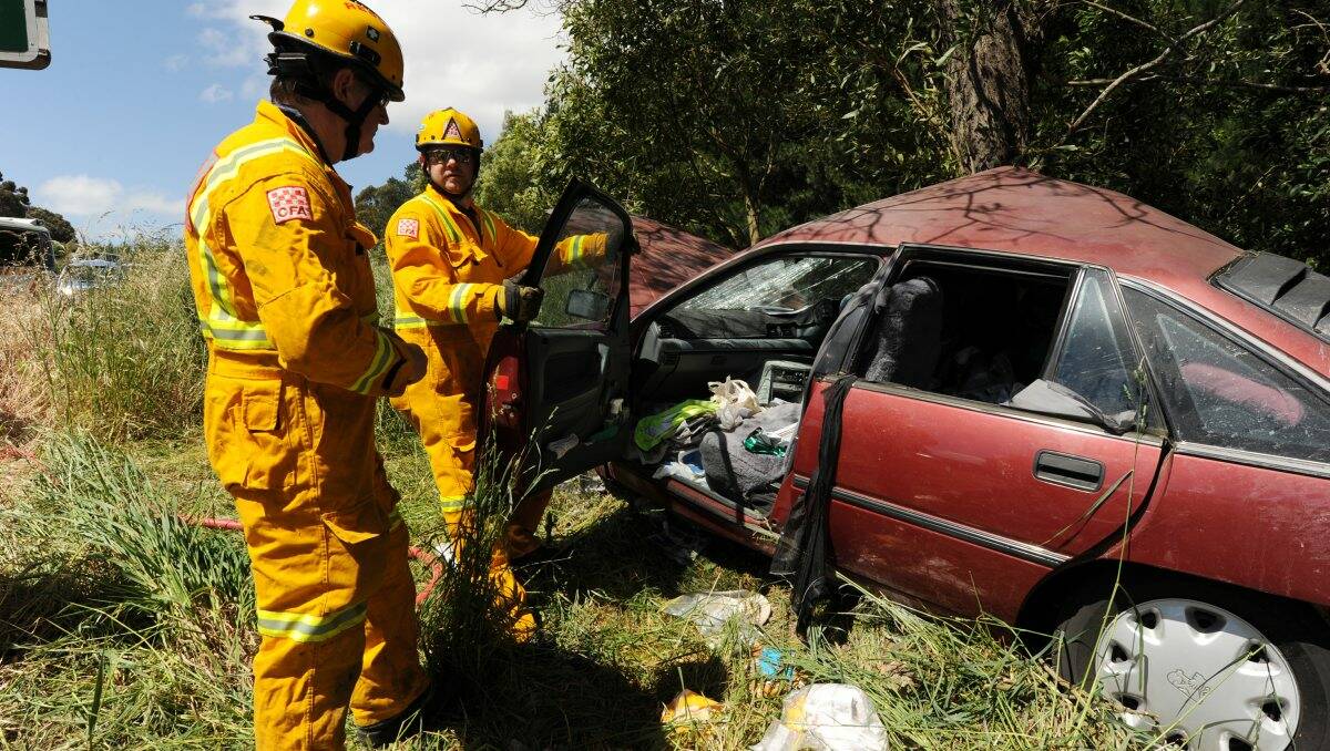 Scene: CFA members work on the wrecked car while, inset, its driver is loaded into an ambulance for the trip to hospital. PICTURES: JUSTIN WHITELOCK
