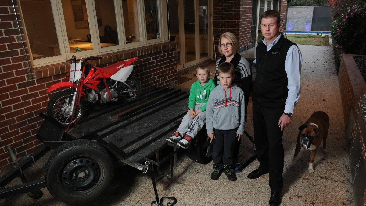 Justin and Jo Kroussoratis with their children Ryan, 5, and Jordan, 7, next to the trailer from where a motorbike was stolen.