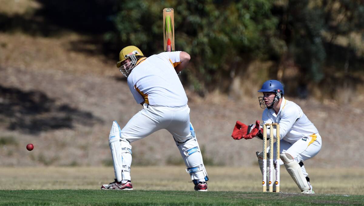East Ballarat’s Josh Brown raises his bat as Napoleons-Sebastopol wicketkeeper Ben Trew looks on at the weekend. 
